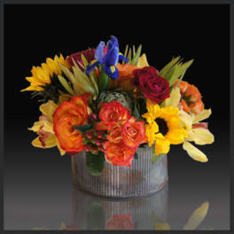 Colorful bouquet in a ribbed metal container with sunflowers and roses