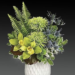 Green and blue floral arrangement in a white textured vase