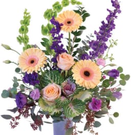 Mixed bouquet of peach and purple flowers in a lavender vase