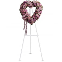 Heart-shaped pink rose wreath on a white easel with ribbon