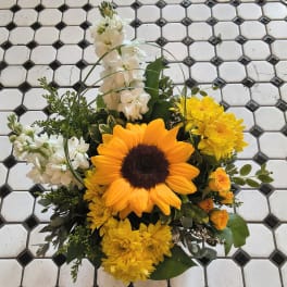 Sunflower arrangement with white and yellow flowers on a tiled surface