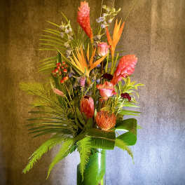 Tall tropical flower arrangement in a clear glass vase