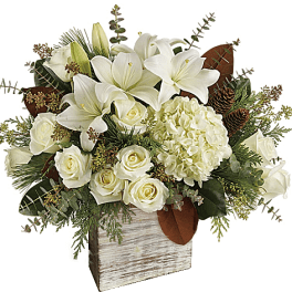 White lilies and roses in a rustic wooden vase with greenery