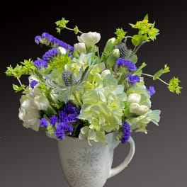 White and purple flowers arranged in a snowflake mug vase