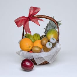 Fruit basket with oranges, mango, kiwi, and bottled juice tied with a red bow
