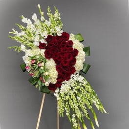 Standing floral spray with red roses and white flowers on an easel