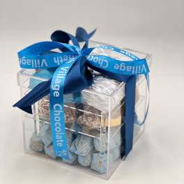 Clear gift box filled with assorted chocolates and tied with a blue ribbon