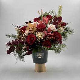 Red roses and pink orchids in a black vase with gold base