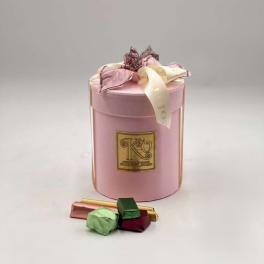 Pink gift box with ribbon and assorted chocolates in front