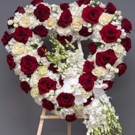 Heart-shaped floral arrangement of red and white roses on an easel