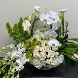 White orchids, calla lilies, roses, and green blooms in a low arrangement