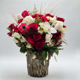 Red and white rose bouquet in a rustic twig vase