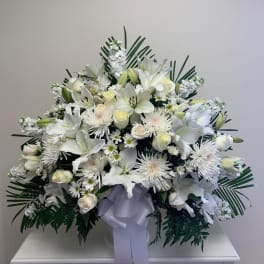 Large white floral spray with lilies and daisies, tied with a lavender ribbon