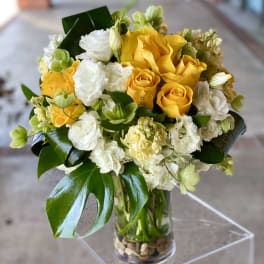 Yellow and white roses arranged in a clear glass vase