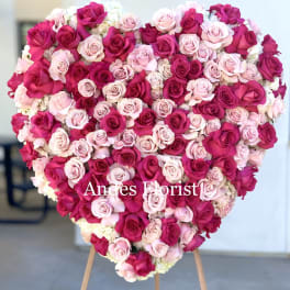 Heart-shaped arrangement of pink and magenta roses on an easel
