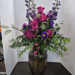 Purple and pink floral arrangement in a dark glass vase
