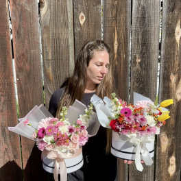 Woman holding two pastel flower boxes with mixed blooms