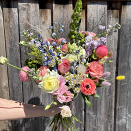 Handheld bouquet of mixed pastel flowers with tall greenery