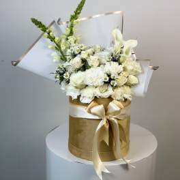 White floral bouquet in a gold hatbox with a satin bow
