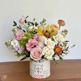 Mixed bouquet of pink, white, and yellow flowers in a decorated ceramic vase
