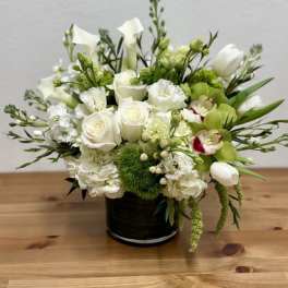 White and green floral arrangement in a black vase