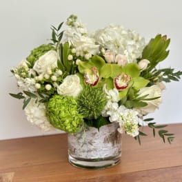 White and green floral arrangement in a glass vase