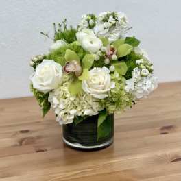 White roses and green hydrangeas arranged in a dark glass vase