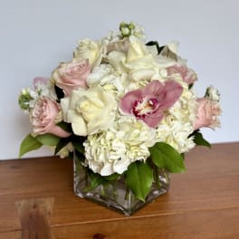 Pink and white roses with hydrangeas in a square glass vase