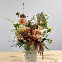 Peach and white floral arrangement in a white vase