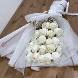 Bouquet of white roses wrapped in white mesh and paper