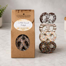 Box of chocolate-covered pretzels beside a stacked display of decorated pretzels