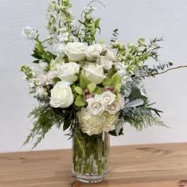 White floral arrangement in a clear glass vase with mixed blooms and greenery