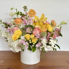Mixed bouquet of yellow, pink, and white flowers in a white vase