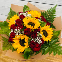 Bouquet of red roses and yellow sunflowers wrapped in brown paper