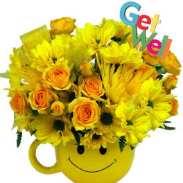 Yellow roses and daisies in a yellow smiley-face mug with a colorful Get Well pick