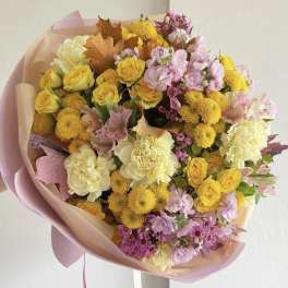 Bouquet of yellow, pink, and cream flowers wrapped in blush paper