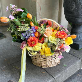 Basket of colorful mixed flowers with a ribbon bow