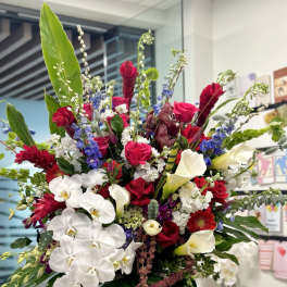 Large mixed bouquet with white orchids, red roses, and calla lilies in a vase