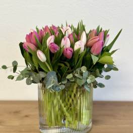 Pink tulips arranged in a clear glass vase with eucalyptus