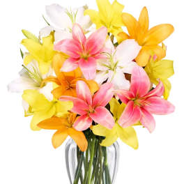 Bouquet of pink, yellow, white, and orange lilies in a clear glass vase