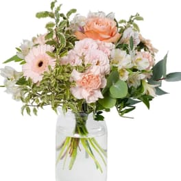 Peach and blush mixed bouquet in a clear glass vase