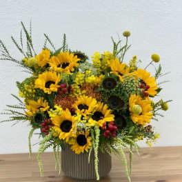 Sunflower arrangement in a ribbed vase with yellow and red accents