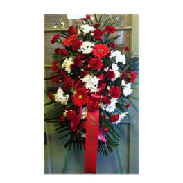 Standing spray of red and white flowers with a red ribbon