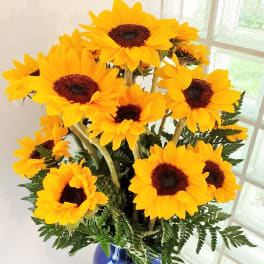 Bouquet of bright yellow sunflowers in a blue vase
