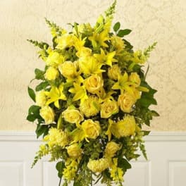 Yellow floral standing spray with roses and lilies on a black easel