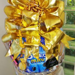 Gift basket wrapped with a large gold bow and assorted snacks