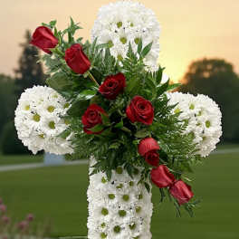White floral cross with red roses on an outdoor stand