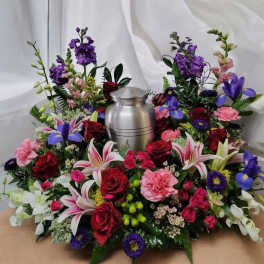 Colorful floral arrangement surrounding a silver urn