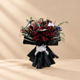 Red flower bouquet with black wrapping and a white ribbon