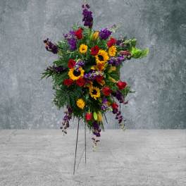 Standing floral spray with red roses, sunflowers, and purple blooms